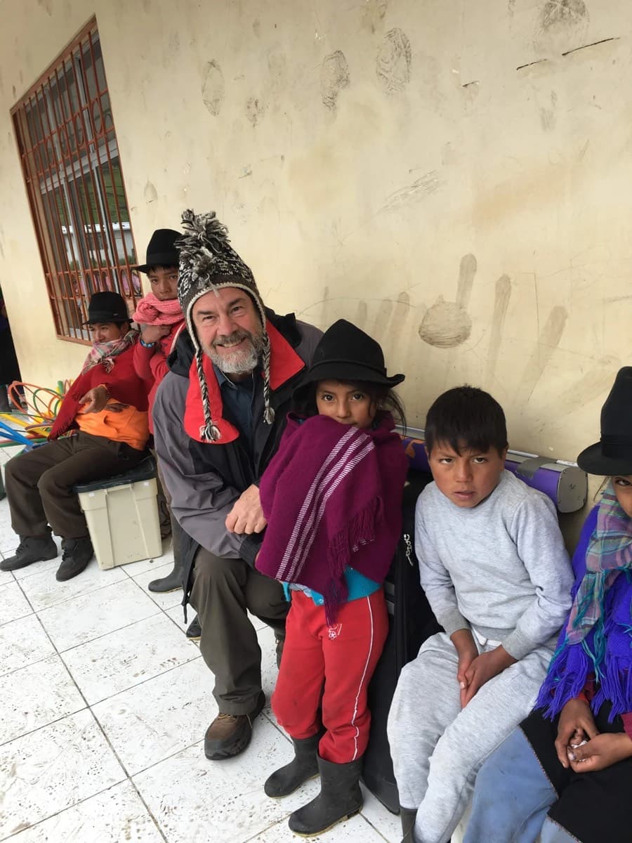 A physician sits with a group of children waiting to be seen