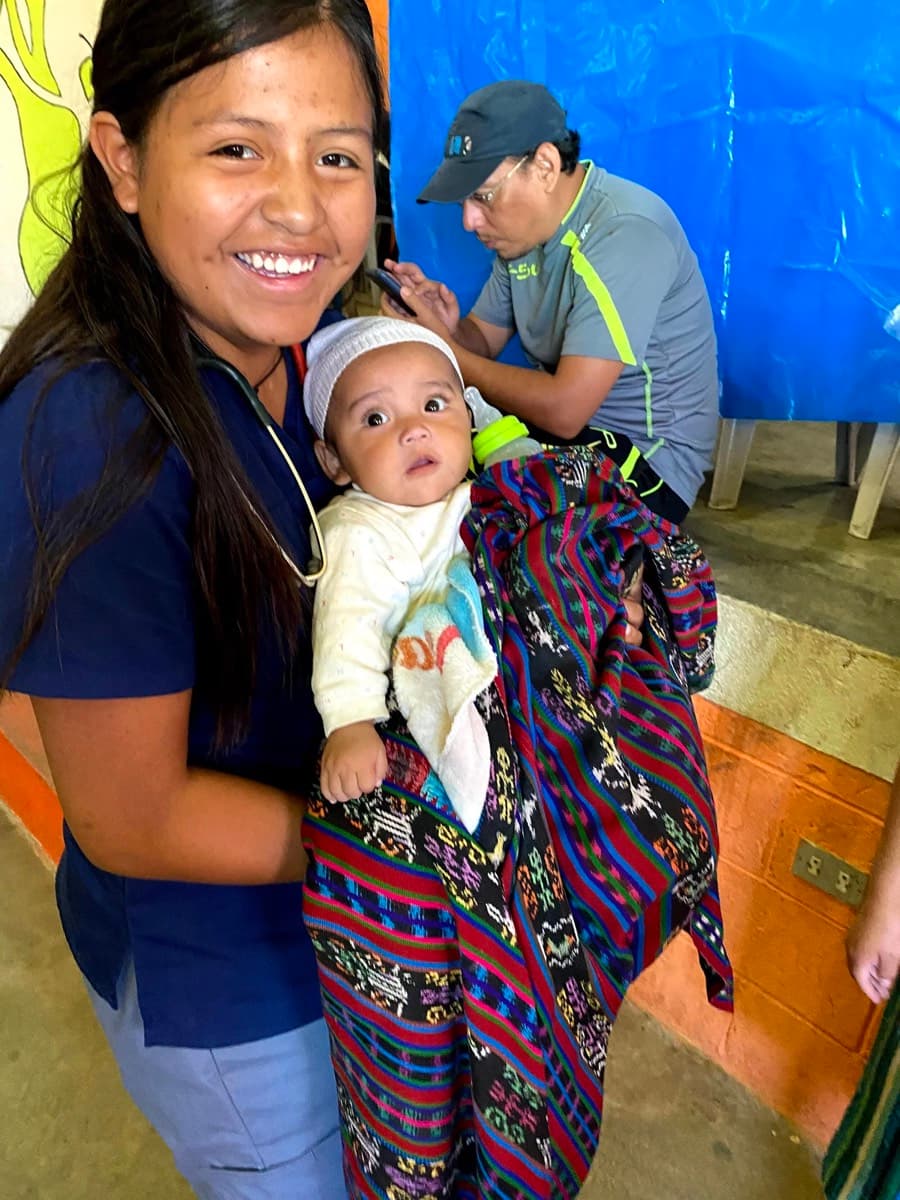 A volunteer holds an infant while speaking with the child's mother