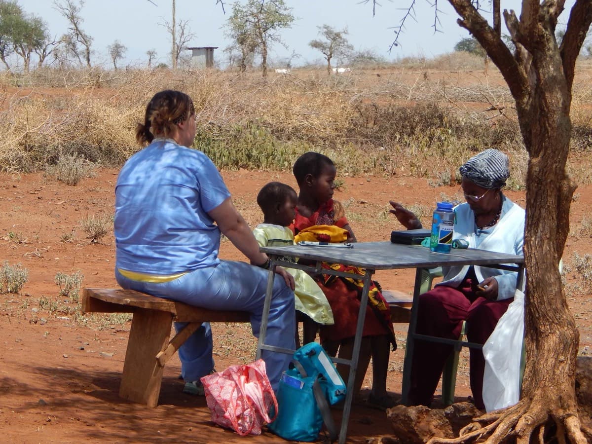 A consultation at a table set up under a tree